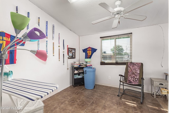 living area featuring ceiling fan and dark tile patterned floors