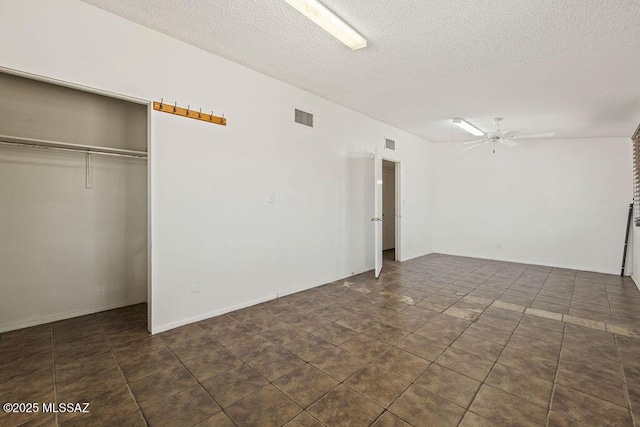 spare room with tile patterned floors, a textured ceiling, visible vents, and a ceiling fan