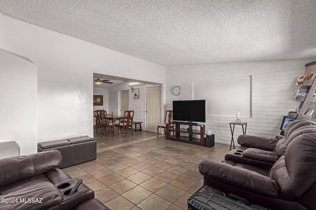 living room with a textured ceiling, ceiling fan, and brick wall