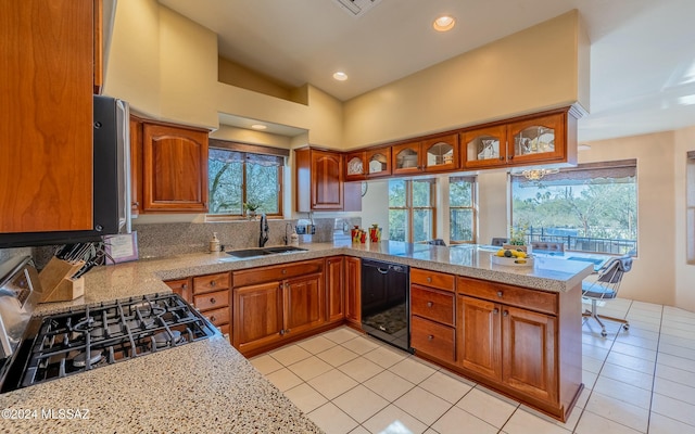 kitchen featuring stainless steel range, sink, black dishwasher, kitchen peninsula, and vaulted ceiling