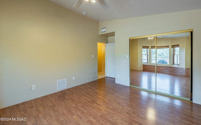 unfurnished bedroom featuring ceiling fan, a closet, lofted ceiling, and hardwood / wood-style flooring