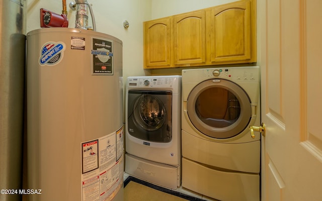 washroom featuring cabinets, washing machine and dryer, and gas water heater