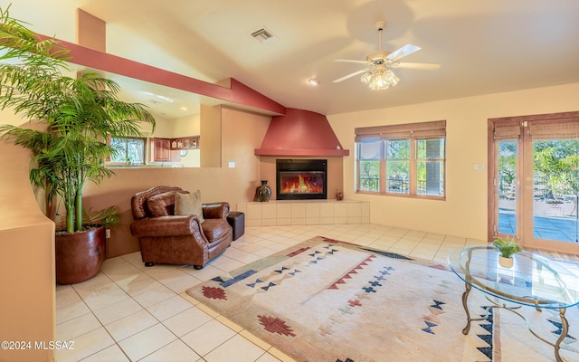 tiled living room with a tile fireplace, ceiling fan, and vaulted ceiling