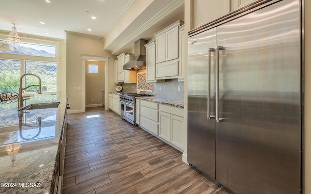 15251 N Dove Canyon Pass, Marana, AZ 85658 - kitchen featuring high quality appliances, wall chimney exhaust hood, a sink, crown molding, and light stone countertops