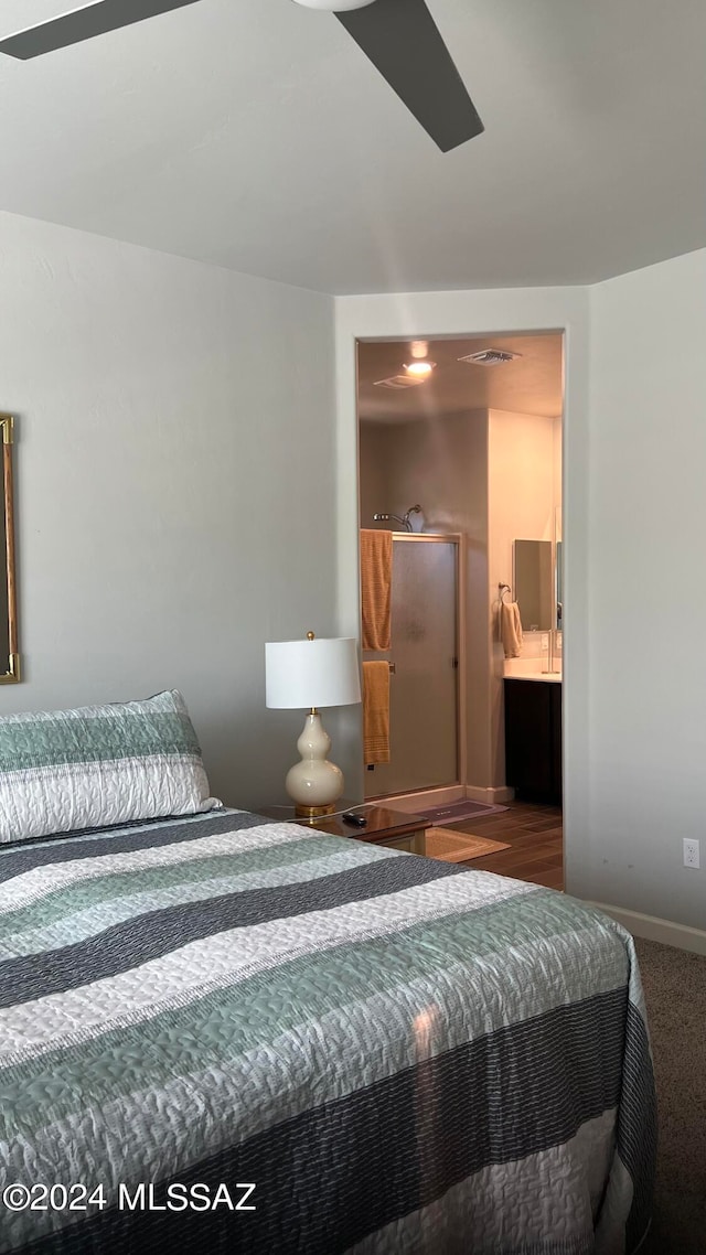 carpeted bedroom with ensuite bathroom and ceiling fan