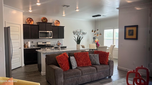 kitchen with backsplash, a kitchen island with sink, sink, appliances with stainless steel finishes, and light stone counters