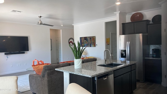 kitchen featuring appliances with stainless steel finishes, light stone counters, ornamental molding, sink, and a center island with sink