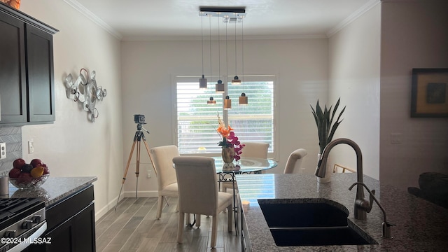 dining space with crown molding, sink, and light hardwood / wood-style flooring