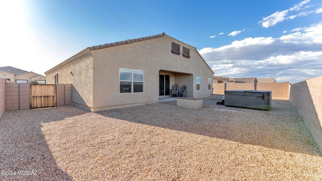 rear view of house featuring a patio and a hot tub