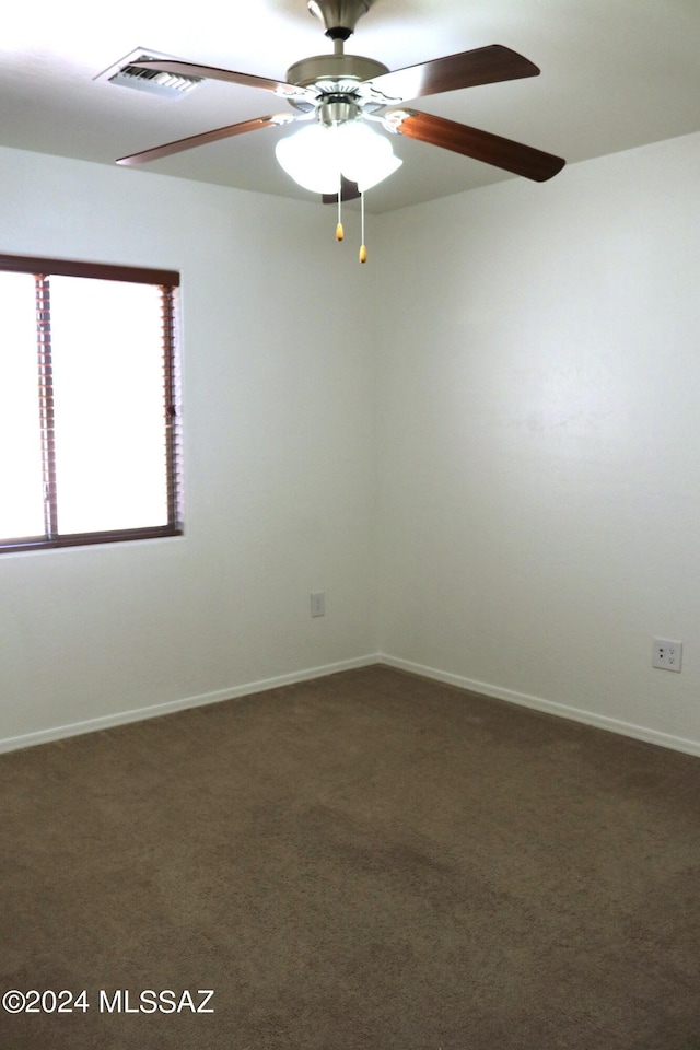 empty room featuring ceiling fan and dark colored carpet