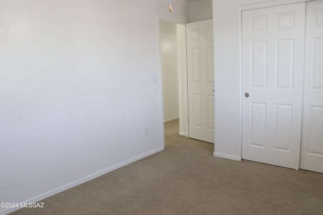 unfurnished bedroom featuring light colored carpet and a closet