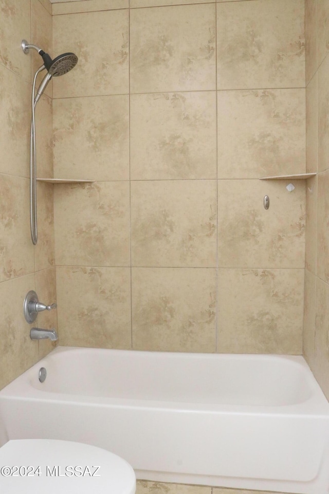 bathroom with tiled shower / bath combo and toilet