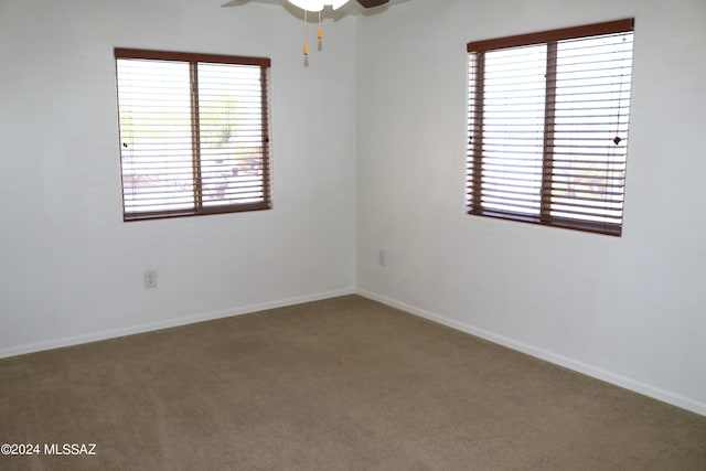 carpeted spare room featuring a wealth of natural light and ceiling fan