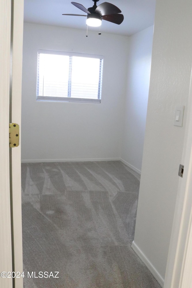 spare room with dark carpet and ceiling fan