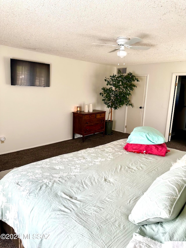 carpeted bedroom with ceiling fan and a textured ceiling