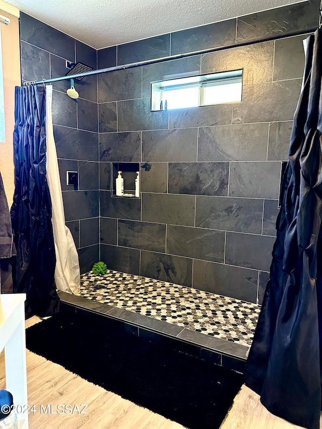 bathroom with a textured ceiling, hardwood / wood-style floors, and curtained shower