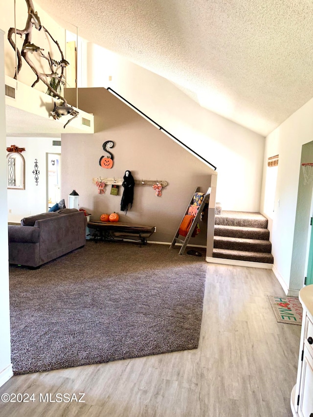 unfurnished living room featuring vaulted ceiling, a textured ceiling, and hardwood / wood-style floors