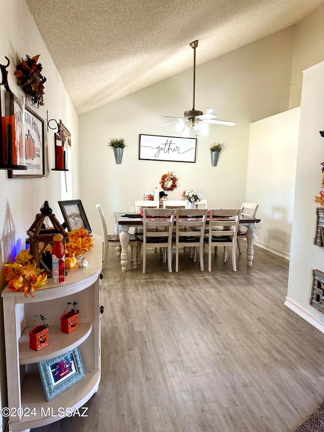 dining area featuring vaulted ceiling, ceiling fan, hardwood / wood-style flooring, and a textured ceiling