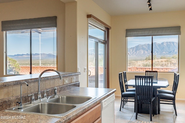 kitchen with a mountain view, white dishwasher, a healthy amount of sunlight, and sink