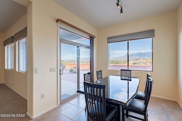 dining room featuring a mountain view, light tile patterned floors, and track lighting