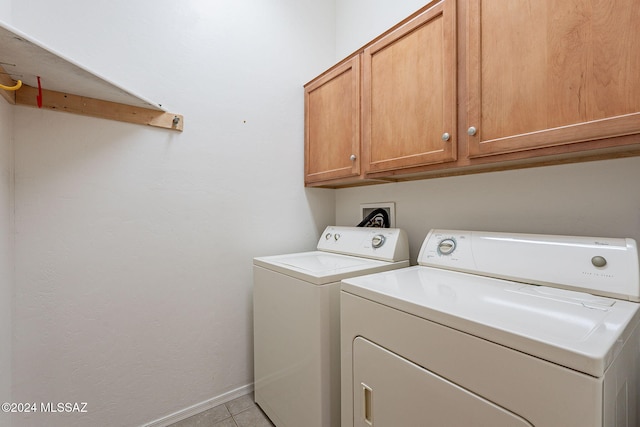 washroom featuring cabinets, light tile patterned floors, and washing machine and clothes dryer