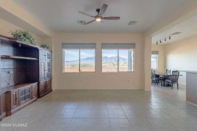 living room with a mountain view, rail lighting, ceiling fan, and light tile patterned flooring