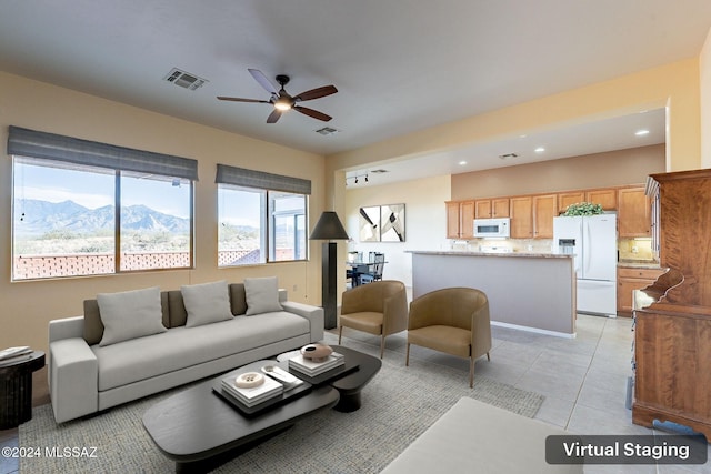 tiled living room with a mountain view and ceiling fan