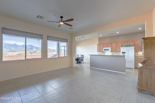 interior space with a mountain view, light tile patterned floors, and ceiling fan