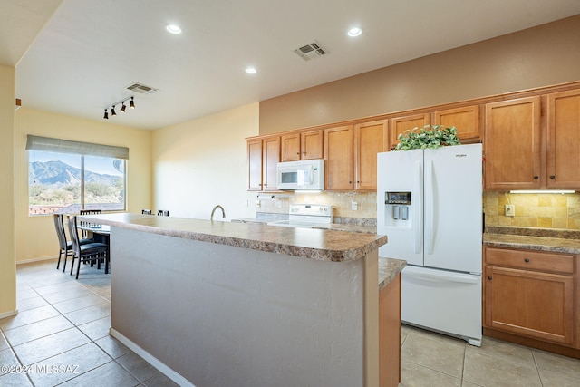 kitchen with white appliances, an island with sink, light tile patterned floors, and tasteful backsplash