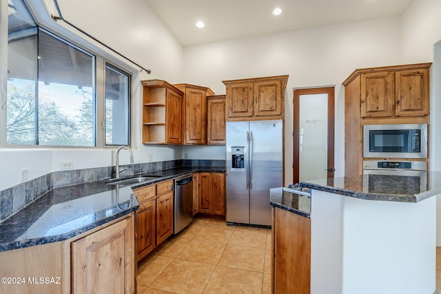 kitchen featuring light tile patterned floors, stainless steel appliances, dark stone countertops, and sink