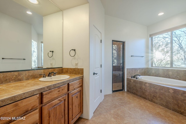 bathroom featuring tile patterned floors, vanity, and tiled bath