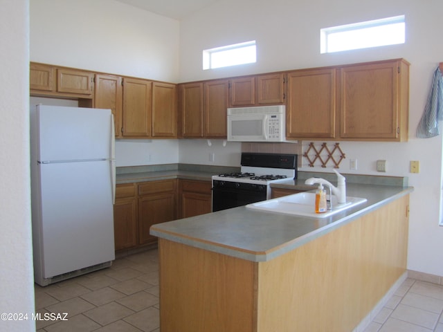 kitchen with light tile patterned flooring, high vaulted ceiling, white appliances, kitchen peninsula, and sink