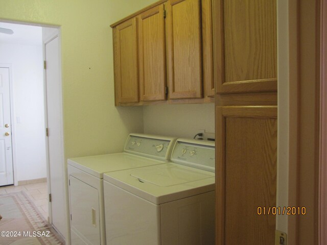 laundry room with light tile patterned flooring, washer and dryer, and cabinets