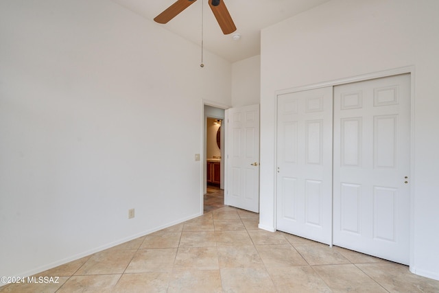 unfurnished bedroom with a high ceiling, light tile patterned floors, a closet, and ceiling fan