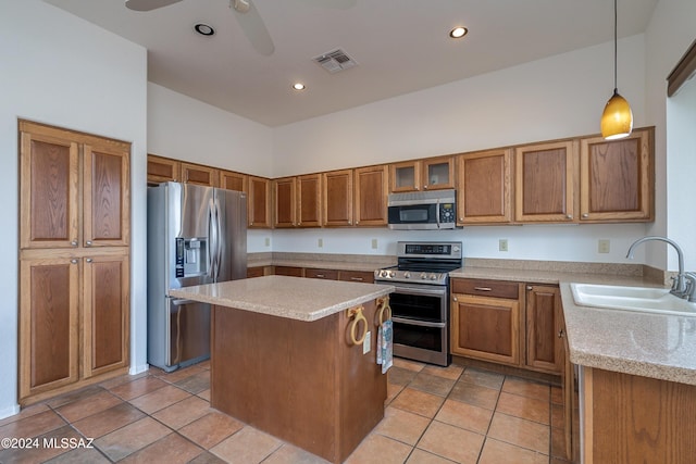 kitchen featuring appliances with stainless steel finishes, a towering ceiling, sink, decorative light fixtures, and a center island