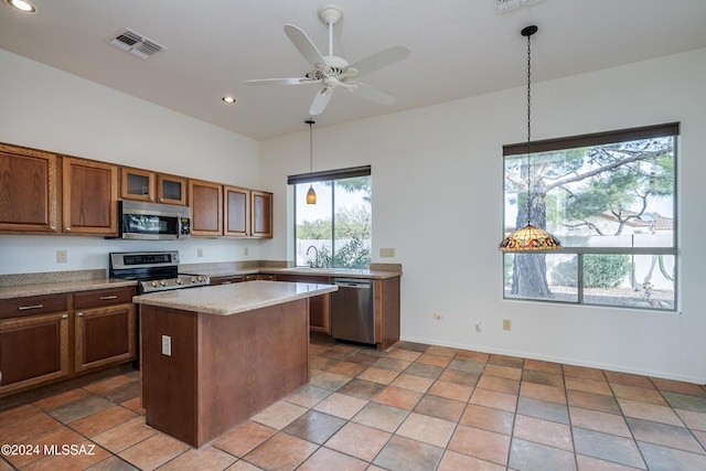 kitchen with decorative light fixtures, a healthy amount of sunlight, a kitchen island, and stainless steel appliances