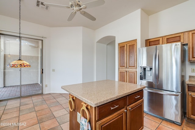 kitchen with ceiling fan, a kitchen island, stainless steel fridge with ice dispenser, decorative light fixtures, and light tile patterned floors