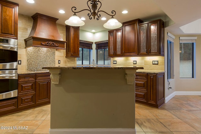 kitchen with custom exhaust hood, a kitchen island, pendant lighting, and stainless steel appliances