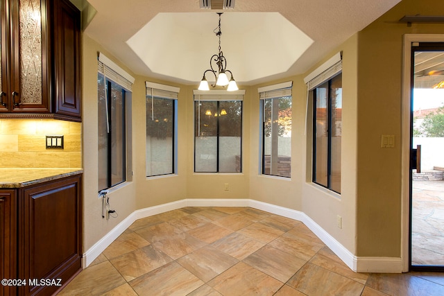 unfurnished sunroom with a chandelier and a tray ceiling