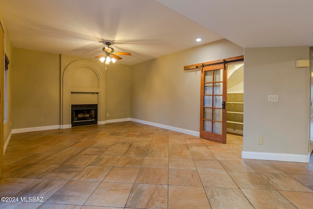 unfurnished living room with ceiling fan and a barn door