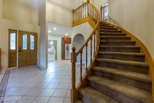 tiled entryway featuring a towering ceiling