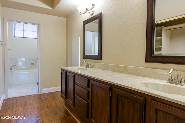 bathroom with vanity, a tub to relax in, hardwood / wood-style flooring, and a textured ceiling