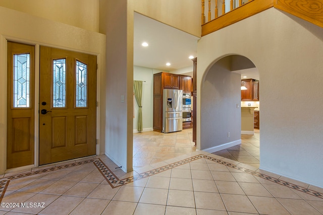 entrance foyer with a towering ceiling and light tile patterned floors