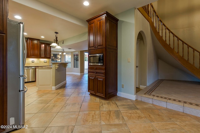 kitchen featuring light tile patterned flooring, decorative backsplash, stainless steel appliances, and hanging light fixtures