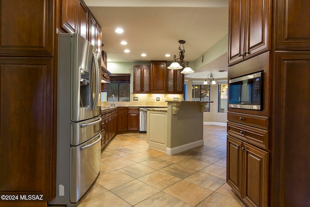 kitchen featuring stainless steel appliances, light stone countertops, a kitchen bar, pendant lighting, and a center island