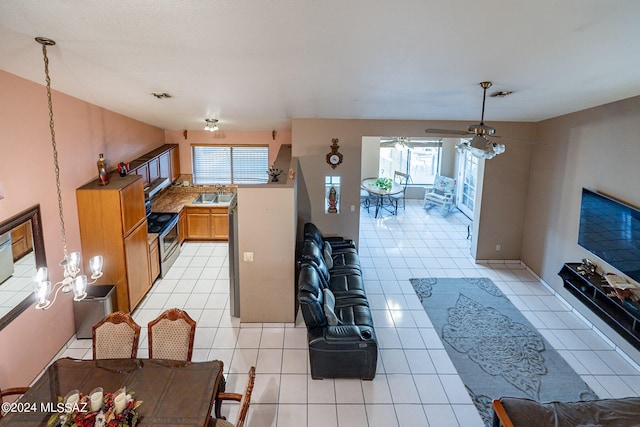 kitchen with a healthy amount of sunlight, light tile patterned flooring, stainless steel range with electric stovetop, and sink