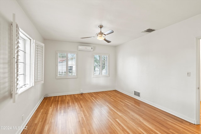 empty room featuring ceiling fan, light hardwood / wood-style floors, and an AC wall unit