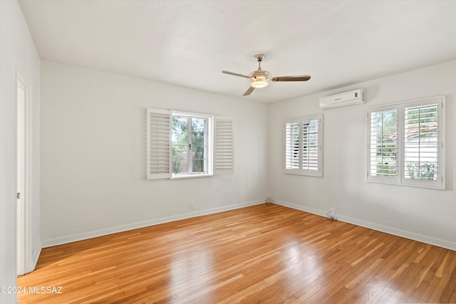 unfurnished room with ceiling fan, light hardwood / wood-style floors, and a wall unit AC