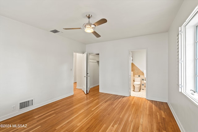 unfurnished bedroom with light wood-type flooring, a closet, ceiling fan, and ensuite bathroom