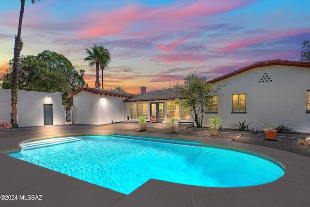 pool at dusk featuring a patio